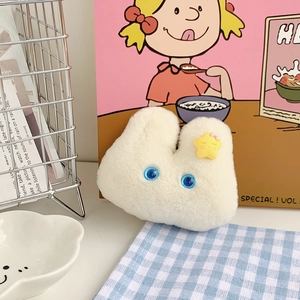 Detail of white plush bunny keychain with blue eyes and yellow star bow accessory