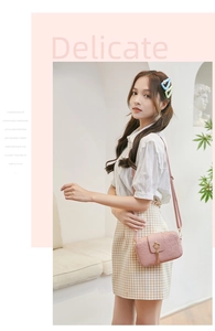 Detailed view of pink camera bag with embossed patterns, gold crown lock, and tassel