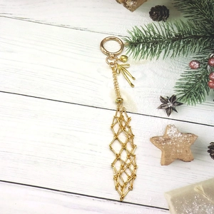 Porte-clés doré élégant avec nœud et pendentif géométrique sur fond de fête chic