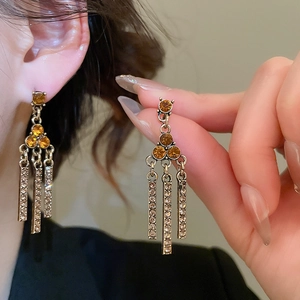 Detail of vintage gold earrings with amber stones and sparkling rhinestone fringes
