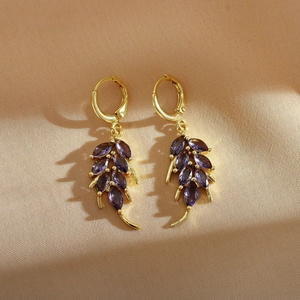Macro shot of gold wheat-leaf earrings with marquise-cut purple stones and secure clasps
