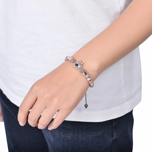 Detail of beaded photo projection bracelet with silver flower charm on female wrist