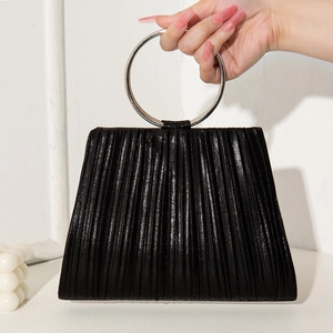 Chic black pleated evening handbag with round metal handle held by model in professional studio