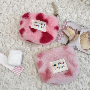 Detailed view of plush pink leopard print coin purses on a soft white furry rug background