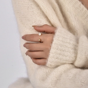 Minimalist gold open ring featuring a pearl and metal bead detail on model's finger
