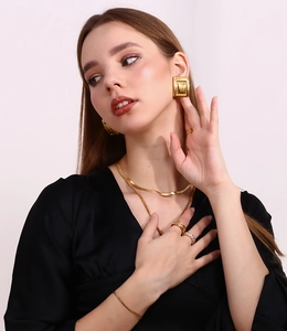Close-up of elegant gold geometric earrings and matching jewelry set worn by a model