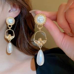 Detail of baroque vintage earrings with angel relief and hanging teardrop pearl