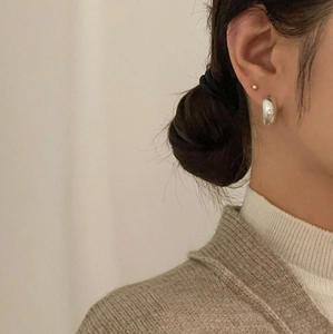 Close-up of minimalist 925 sterling silver wide hoop earrings on a model profile
