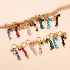 Détail de boucles d'oreilles dorées avec pierres naturelles et pendentifs en fleurs