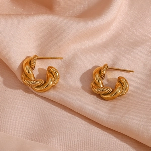 Detailed view of golden twisted earrings on soft pink silk showing spiral texture