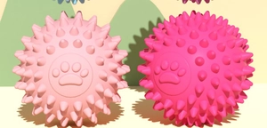 Close-up of pink TPR dog toy ball with soft massage spikes and paw print detail