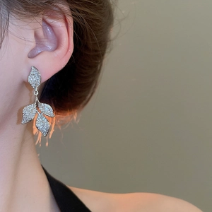 Macro detail of silver leaf tassel earrings with sparkling zircon crystals on a model