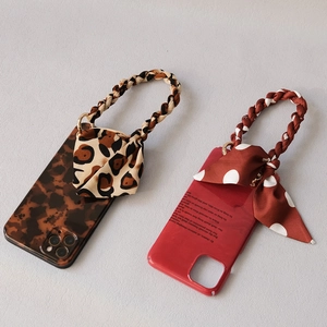 Detail of leopard print and red polka dot phone cases with silk scarf chain straps