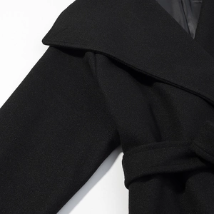 Detailed close-up of a black wool coat featuring the lapel, shoulder, and matching waist belt