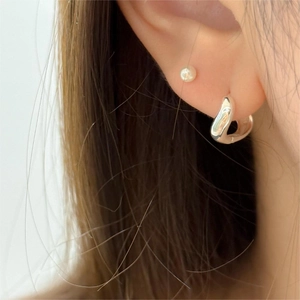 Vue rapprochée du clou d'oreille minimaliste en argent 925 courbé sur le lobe