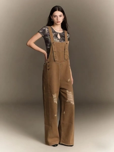Detail of vintage brown distressed denim overalls featuring ripped knees and loose wide-leg fit