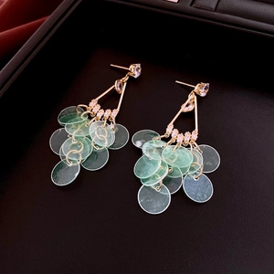 Detail of bamboo hoop earrings with green shell discs and crystals in gold finish