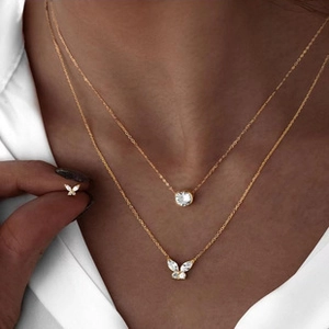 Close-up of double-layered gold necklace with butterfly and round zircon pendants