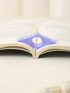 Macro di un ferma pagine da pollice in acrilico viola su un libro aperto