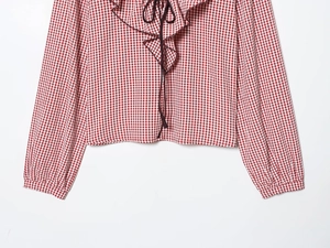 Detail of red and white checkered shirt featuring ruffled neckline and delicate tie strings