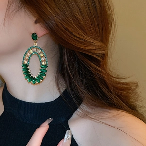 Close-up of vintage emerald green rhinestone earrings with gold hollow design