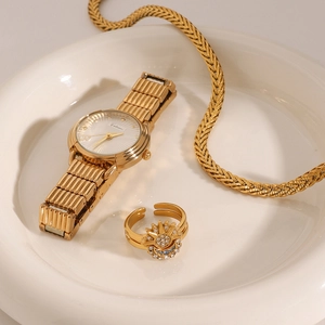 Detail of gold moon and sun ring paired with chain watch on white ceramic tray