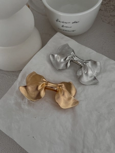 Detailed view of elegant gold and silver bow hair clips on a white textured stone surface