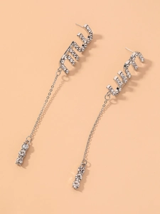 Detailed close-up of M letter silver drop earrings with pavé rhinestones and long chains