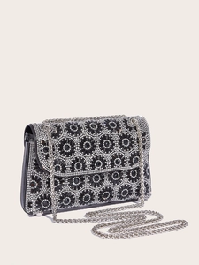 Close-up of black evening clutch bag with sparkling floral crystal patterns and silver chain