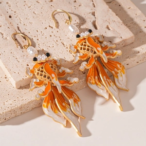 Macro shot of koi carp earrings with orange enamel dripping oil and faux pearl details