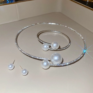 Close-up of sparkling silver necklace, bracelet and stud earrings set with pearls and diamonds
