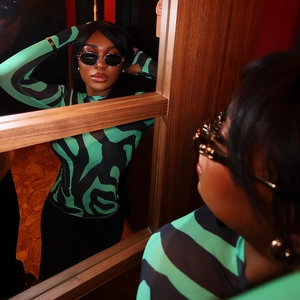 Detail of green and black zebra print bodysuit featuring long sleeves and slim fit design