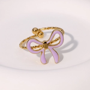 Detail of gold bow ring featuring purple enamel finish and textured adjustable band