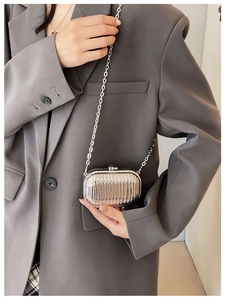 Mini silver luggage-style bag with wave texture and metal chain worn on a blazer