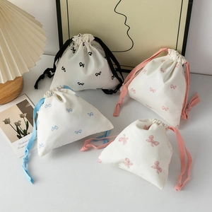 Detailed view of four cotton drawstring bags with elegant bow prints and colorful cords