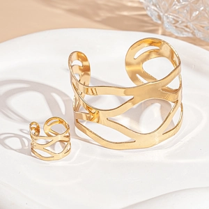 Vue détaillée du bracelet jonc ouvert doré et de la bague sur une assiette en céramique