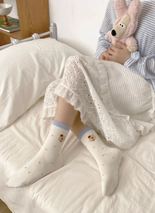 Detail of white mid-calf socks with blue trim, polka dots, and small bear pattern
