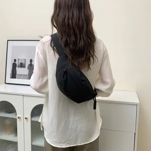 Detail of waterproof black crossbody waist bag with woven zipper pull on model's back