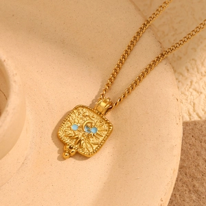 Detail of gold-plated pendant with embossed sun and moon faces and blue accents