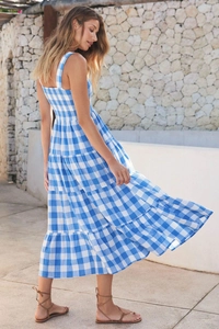 Detail of blue and white plaid midi dress featuring thin straps and tiered cake skirt