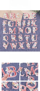 Detail of pink embroidered alphabet patches with 3D flowers on blue denim base