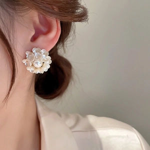 Macro shot of elegant pearl flower earring featuring layered tassels on a model's ear