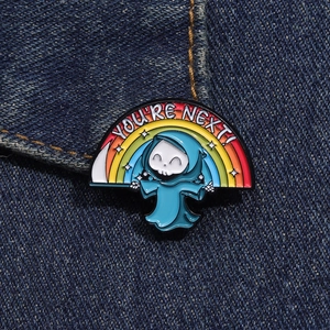 Dettaglio della spilla smaltata mietitore arcobaleno su denim con testo You Are Next