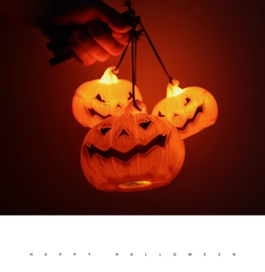 A hand holding three glowing LED pumpkin lanterns with a warm orange light effect.