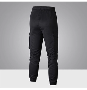 Dettaglio dei pantaloni cargo neri con vita elastica a coulisse e ampie tasche a patta