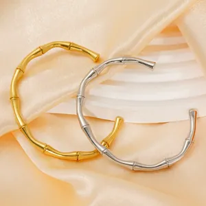 Polished 18K gold and silver bamboo style open cuff bracelets on satin fabric