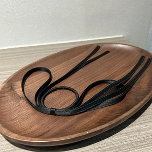 Elegant black satin ribbon hair tie with bow design on a minimalist wooden tray