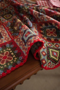Close-up of red Kilim style jacquard tablecloth with geometric patterns and red tassels