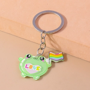 Close-up of a green cartoon frog keychain with a love heart and a rainbow flag detail