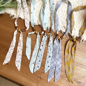 Detail view of multiple printed chiffon necklaces with rustic wood and acrylic beads.
